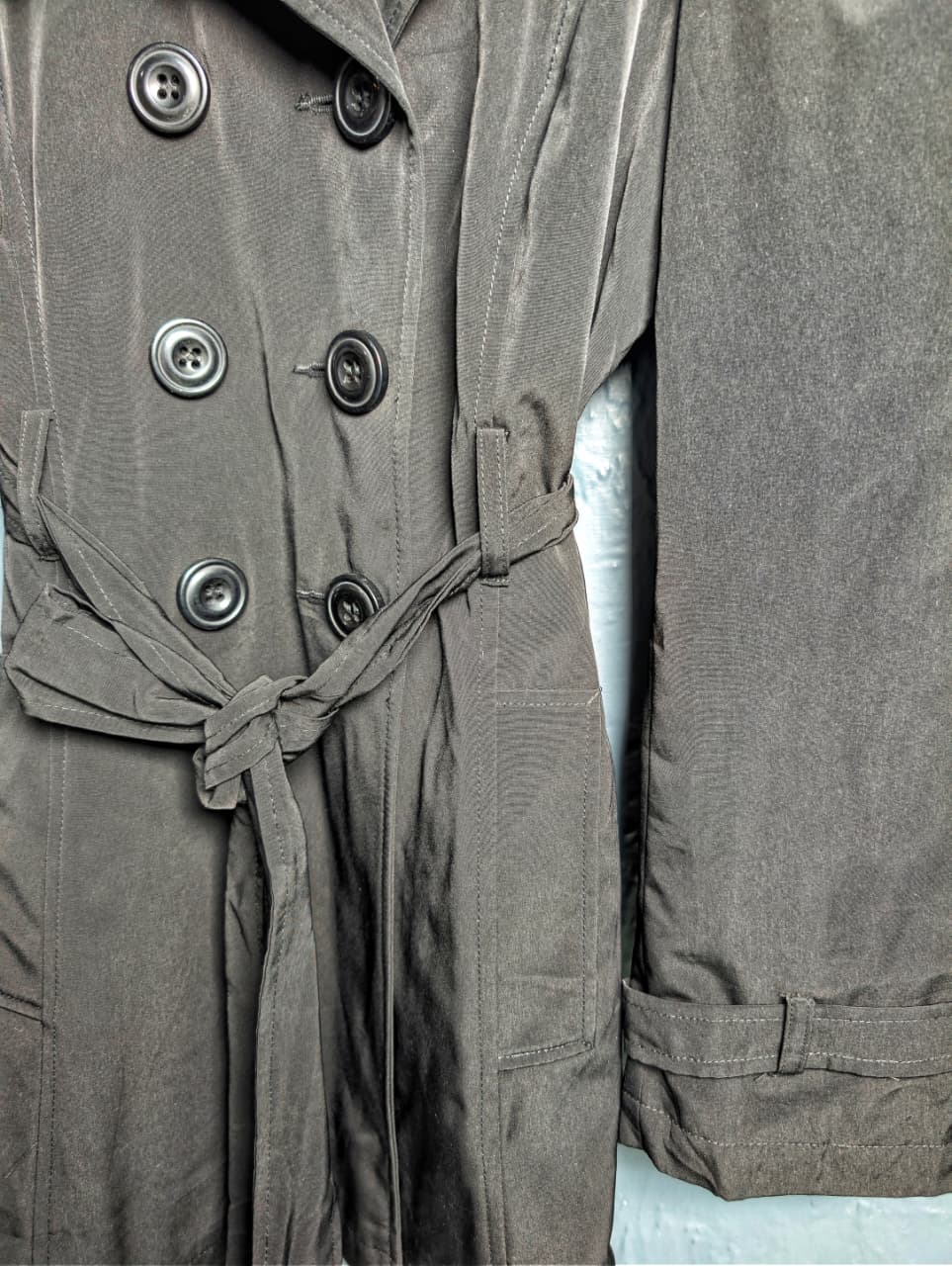George jet black double-breasted trench coat with matching tie belt, and long tab-cuff sleeves