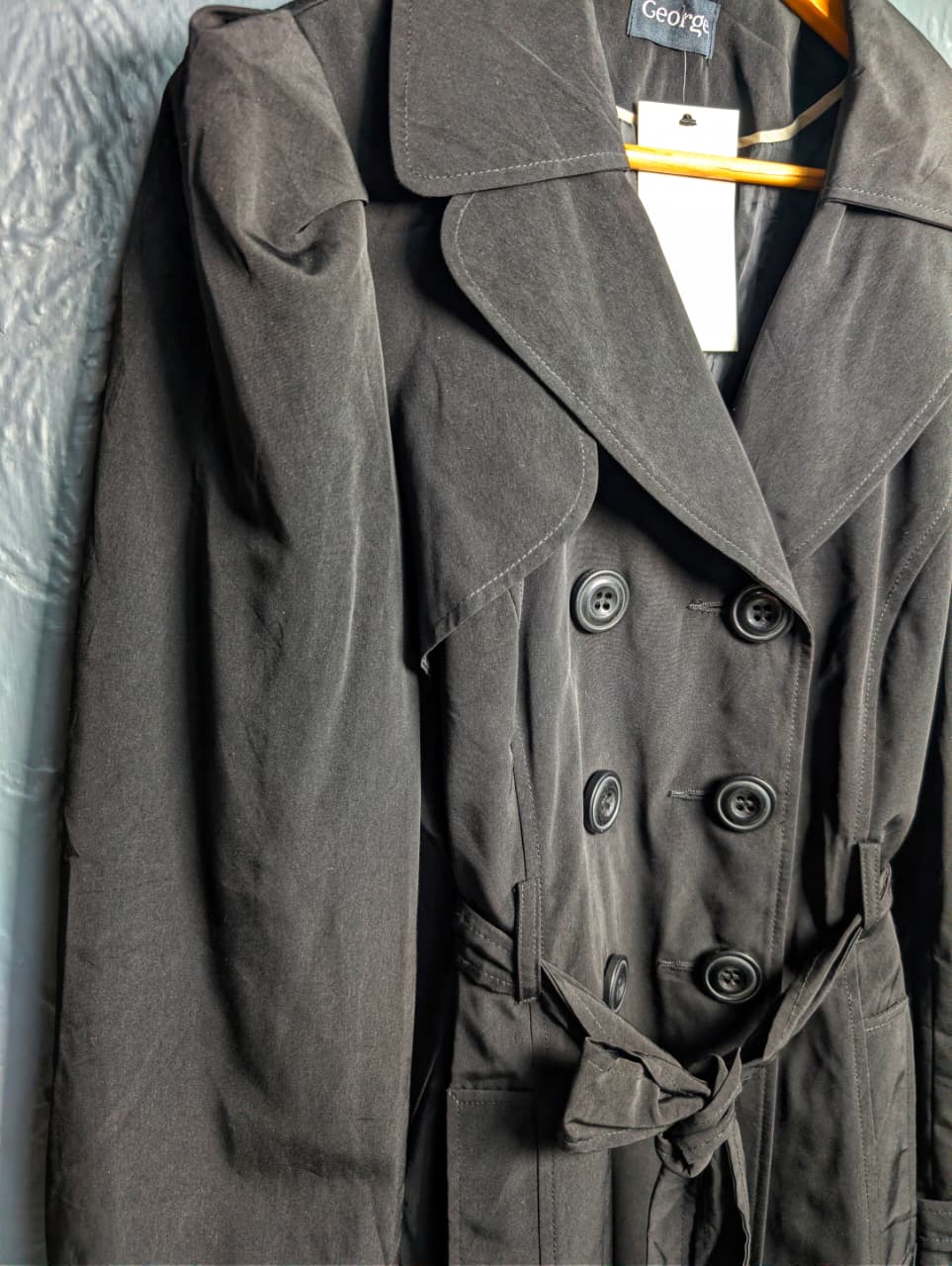 George jet black double-breasted trench coat with matching tie belt, and long tab-cuff sleeves
