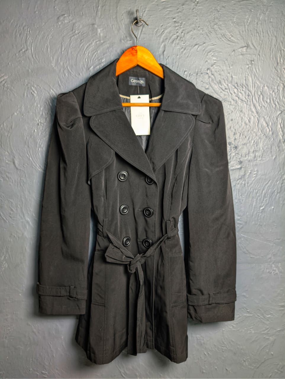 George jet black double-breasted trench coat with matching tie belt, and long tab-cuff sleeves