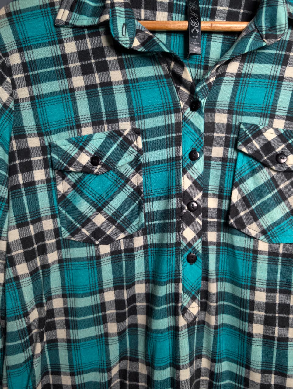 Women's turquoise and black plaid flannel shirt with chest pockets.