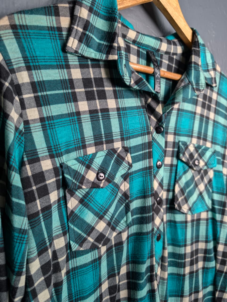 Women's turquoise and black plaid flannel shirt with chest pockets.